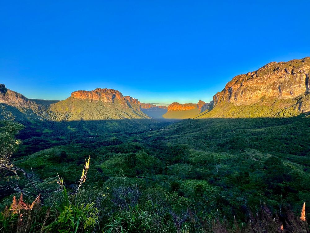 Panoramic view of a lush green valley and flat-topped mountains in Chapada Diamantina National Park at sunrise. 