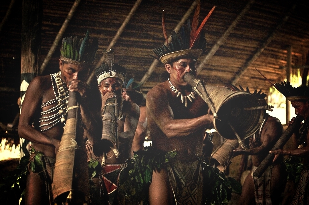  Indigenous people from the Amazon playing traditional wind instruments during a cultural presentation. 