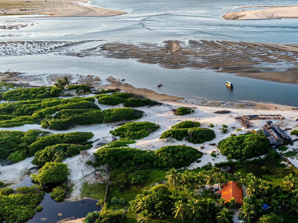 Lush aerial landscape of Atins, highlighting the green vegetation, sandbanks, and the meeting of the Preguiças River waters with the ocean. Lush aerial landscape of Atins, highlighting the green vegetation, sandbanks, and the meeting of the Preguiças River waters with the ocean.