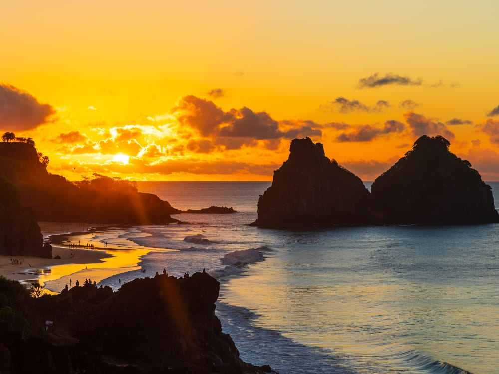 Golden sunset over the Morro Dois Irmaos rock formations, a famous landscape near hotels in Fernando de Noronha. Golden sunset over the Morro Dois Irmaos rock formations, a famous landscape near hotels in Fernando de Noronha.