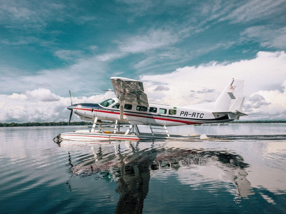 A white and red hydroplane floats on the calm Rio Negro, offering a transport option to the Amazon.