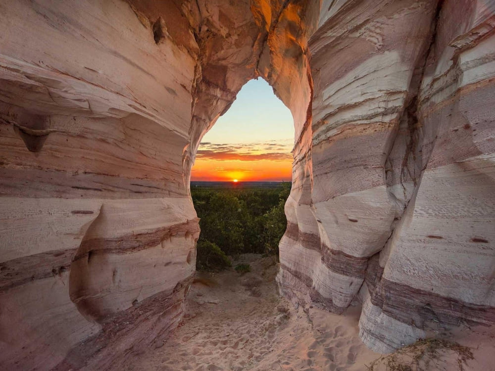 A bright sunset viewed through a natural sandstone wall, highlighting the consistently sunny weather in northern Brazil 