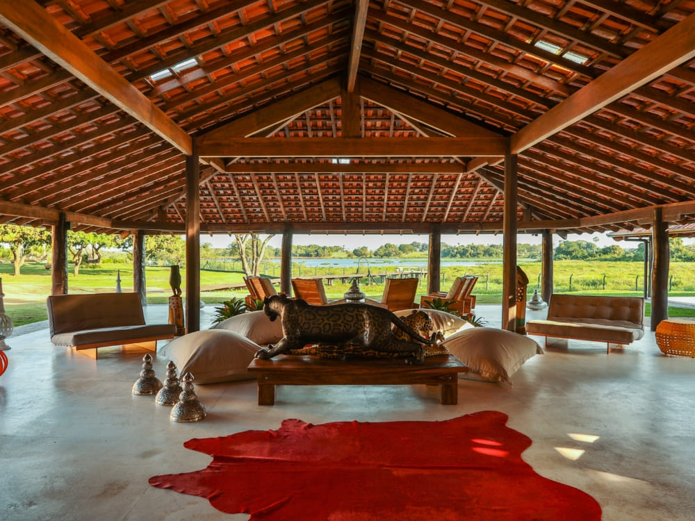The luxurious interior of Caiman lodge features a wooden roof, comfortable seating areas, and a large jaguar statue. The luxurious interior of Caiman lodge features a wooden roof, comfortable seating areas, and a large jaguar statue.