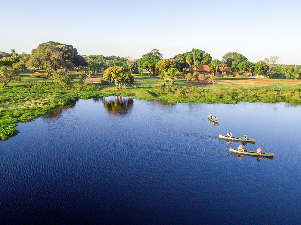 Tourists canoeing near an ecolodge, a sustainable activity for a Pantanal trip that combines adventure with nature preservation.