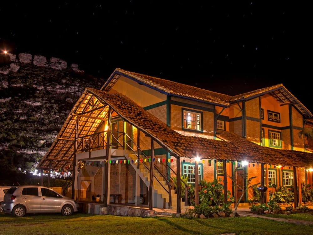 Rustic exterior of Pousada Monte Azul in Mucugê illuminated at night under a dark sky. 