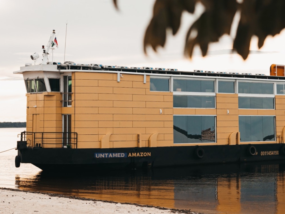 The Untamed Amazon riverboat featuring a modern design with a yellow hull, known for being a sustainable solar-powered cruise option.