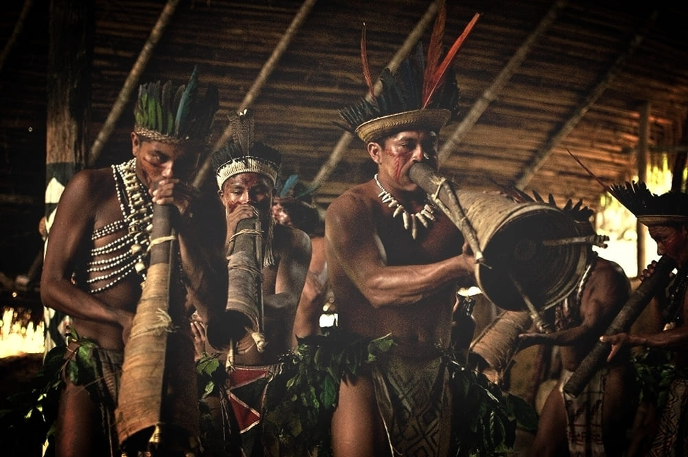 A group of indigenous people in the Amazon playing traditional long wind instruments and drums during a cultural ritual. A group of indigenous people in the Amazon playing traditional long wind instruments and drums during a cultural ritual.