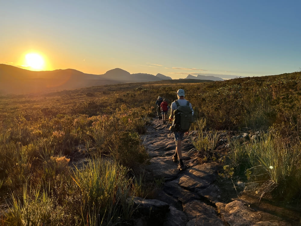 Hikers walking on a rocky trail during sunset in Chapada Diamantina National Park. 