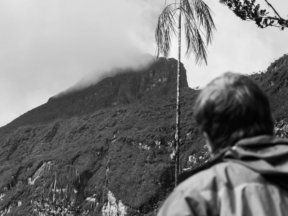 A hiker looks toward the mist-covered summit of Pico da Neblina, the highest peak in Brazil