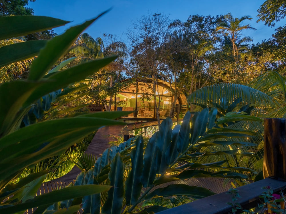 Modern wood and glass architecture of the Mirante do Gaviao hotel illuminated at night in the jungle. Modern wood and glass architecture of the Mirante do Gaviao hotel illuminated at night in the jungle.