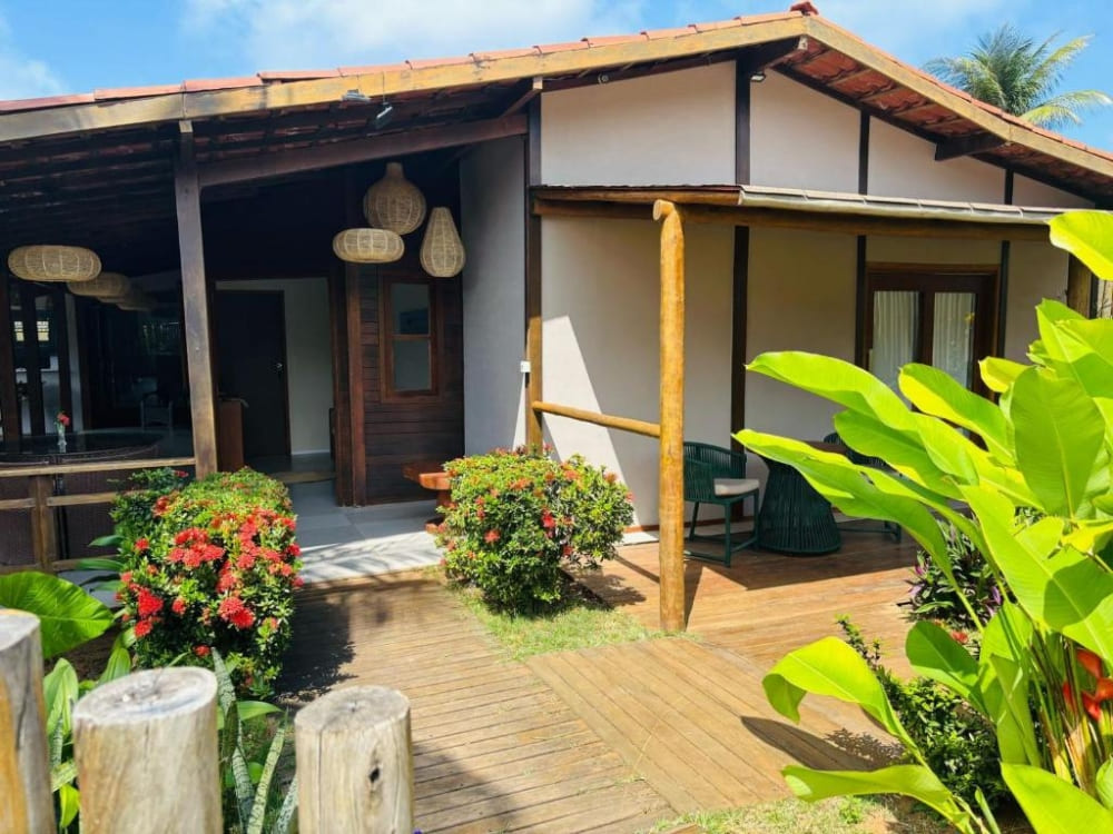 Extérieur d'une charmante maison d'hôtes comprenant un porche couvert, des piliers en bois et un jardin tropical verdoyant à Fernando de Noronha.
