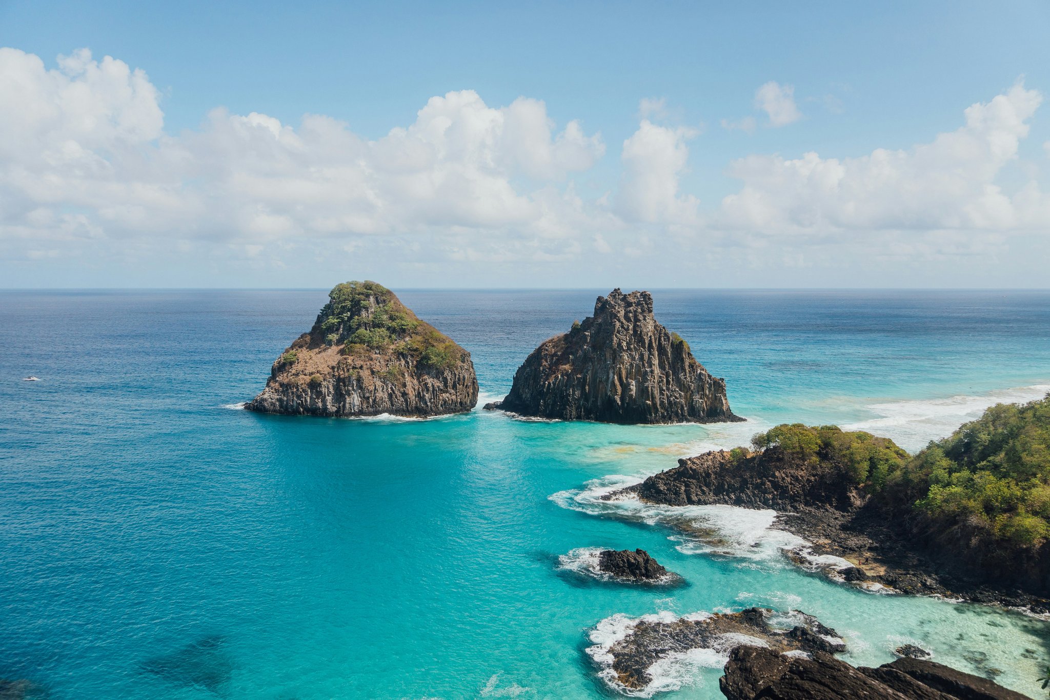 Aerial view of two iconic volcanic rock formations rising from brilliant turquoise waters off Fernando de Noronha, a premier destination for the Adventurer Diving Course in Fernando de Noronha