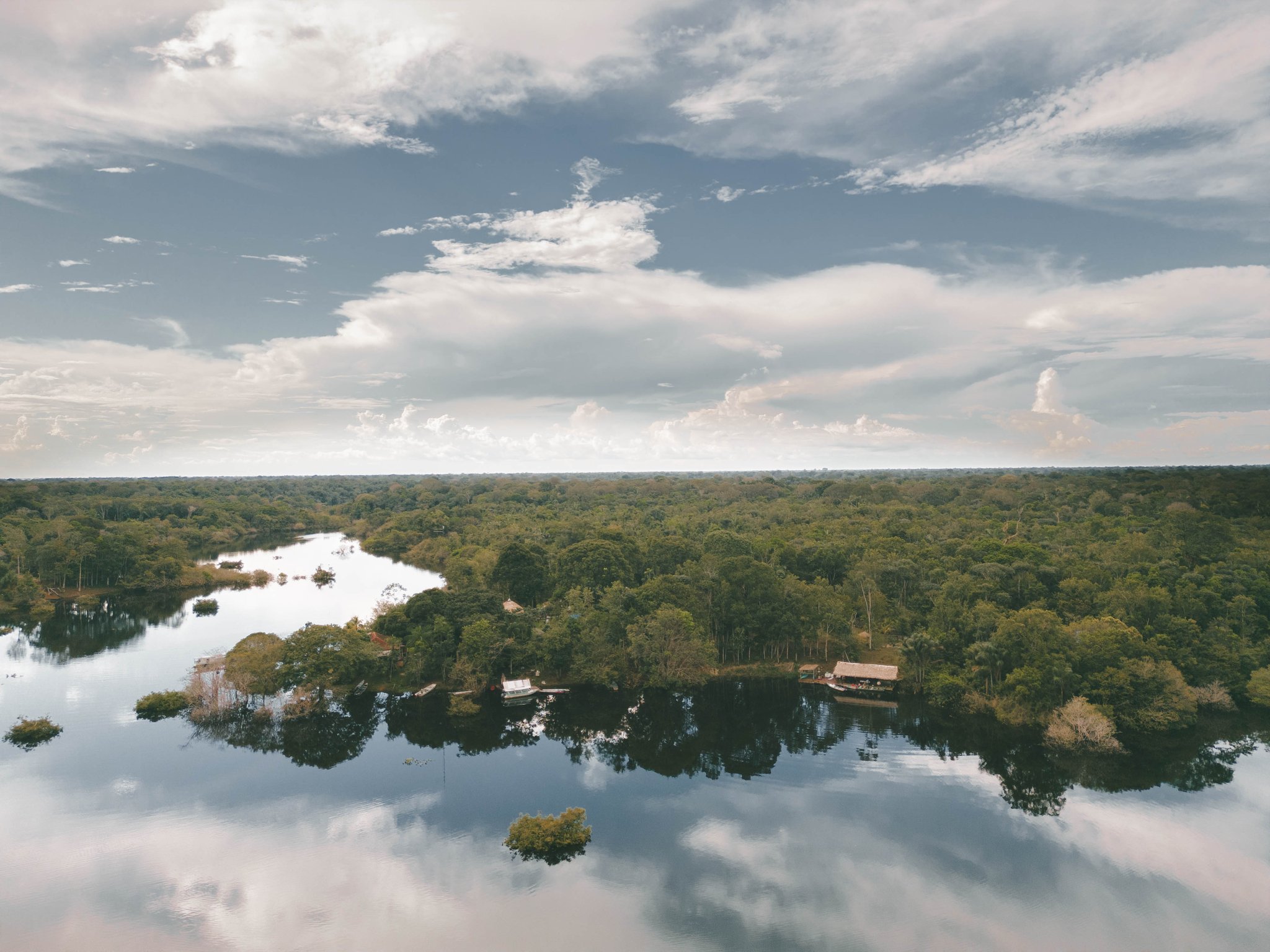 Aerial view of a jungle lodge among forested islands reflected in the calm Rio Negro