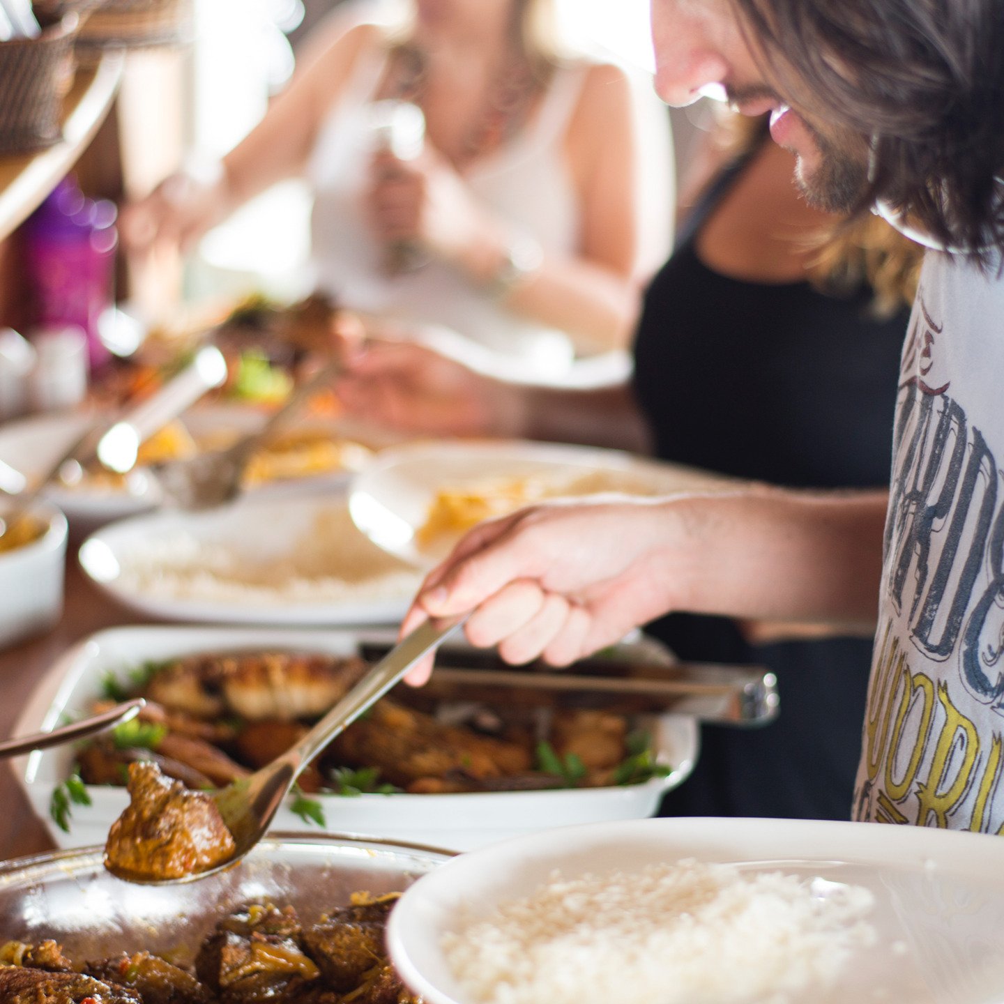 Rich flavors, passed around the table as the river rolls by. Travelers serving themselves from shared platters of braised meat, grilled fish, and rice during a buffet meal on an Amazon cruise trip in Brazil