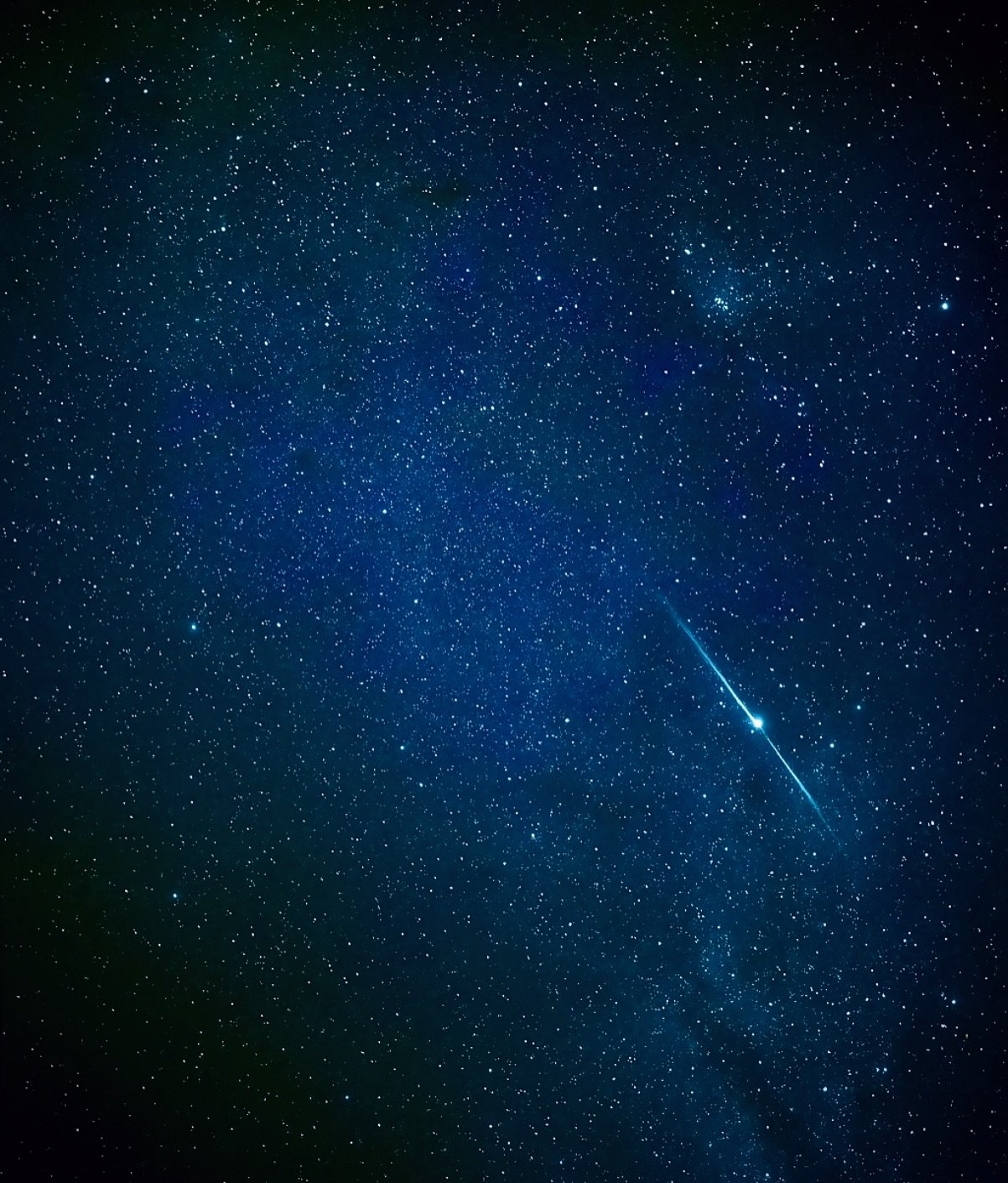 One fleeting streak of light across a billion stars. A bright shooting star streaks diagonally across a deep blue star-filled sky on an Amazon Cruise Trip in Brazil, with the Milky Way glowing softly in the background