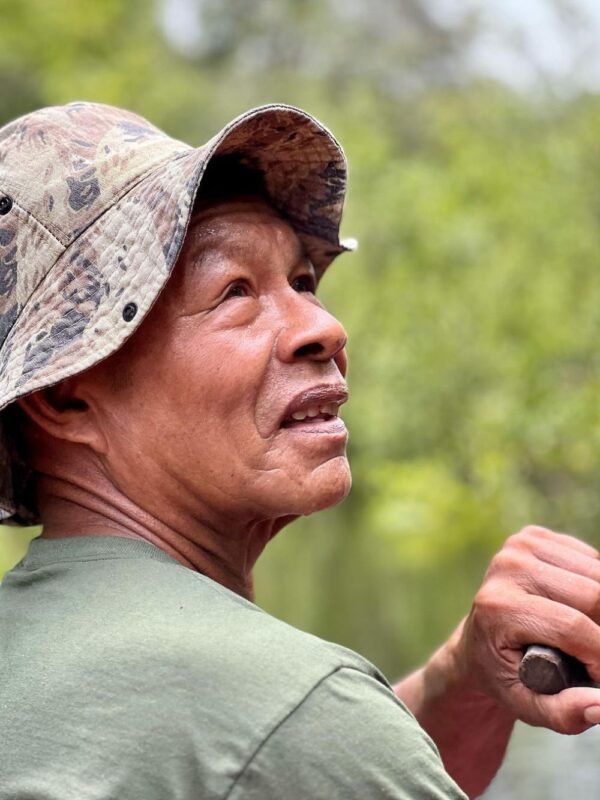 Close portrait of a weathered local Amazon guide in a camouflage hat looking into the distance