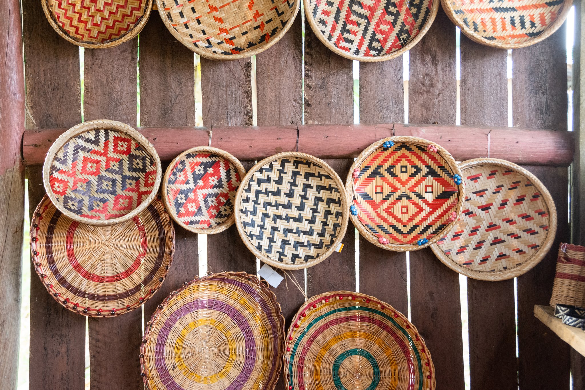 Every pattern tells a story — woven in fiber, passed down through generations. Photo: Vitor Marigo A wall of colorful handwoven round baskets with geometric and concentric patterns displayed at a riverside community near Anavilhanas Jungle Lodge Brazil