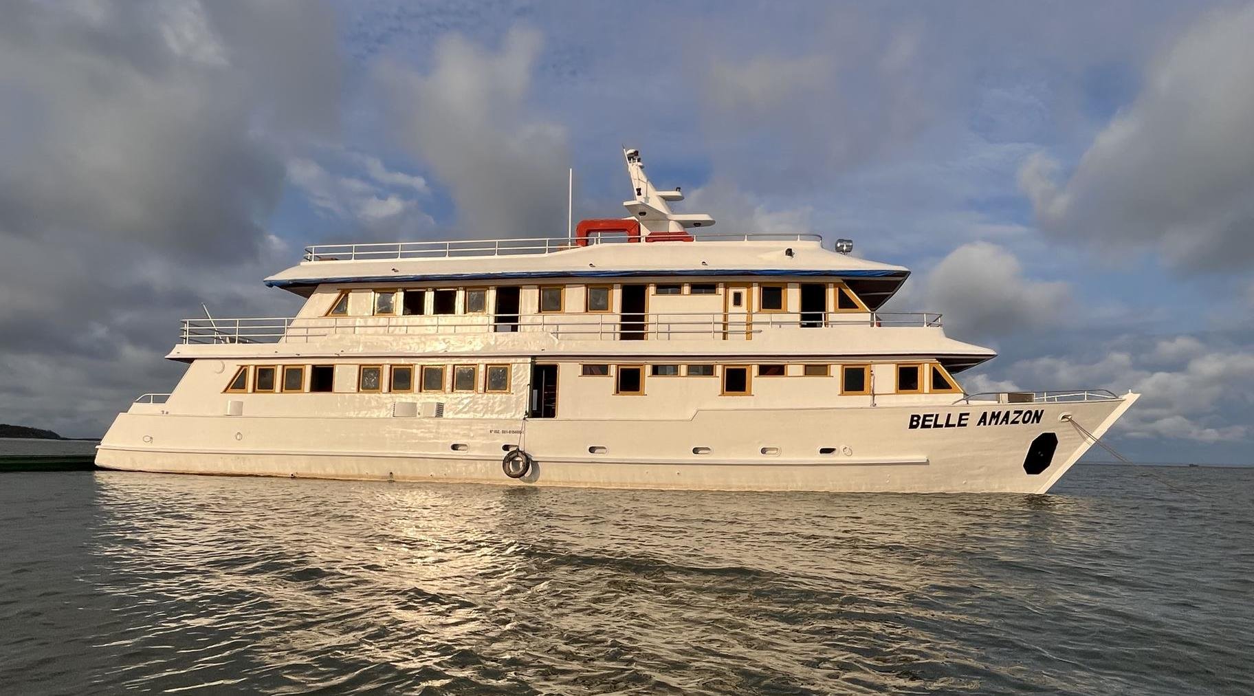 The Belle Amazon multi-deck river cruise ship moored on calm water under a dramatic cloudy sky, part of the Amazon cruise from Alter do Chão experience