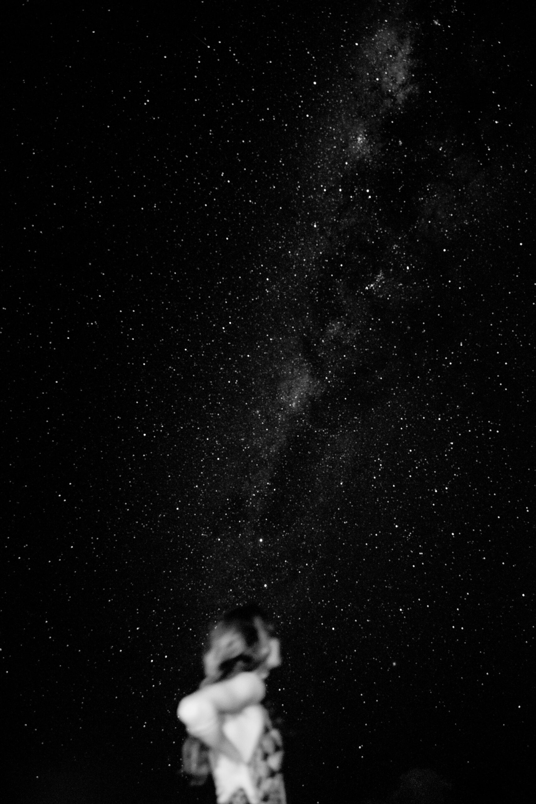 A lone figure silhouetted against the Milky Way on a clear night sky during a brazil luxury tour, black and white long-exposure photograph