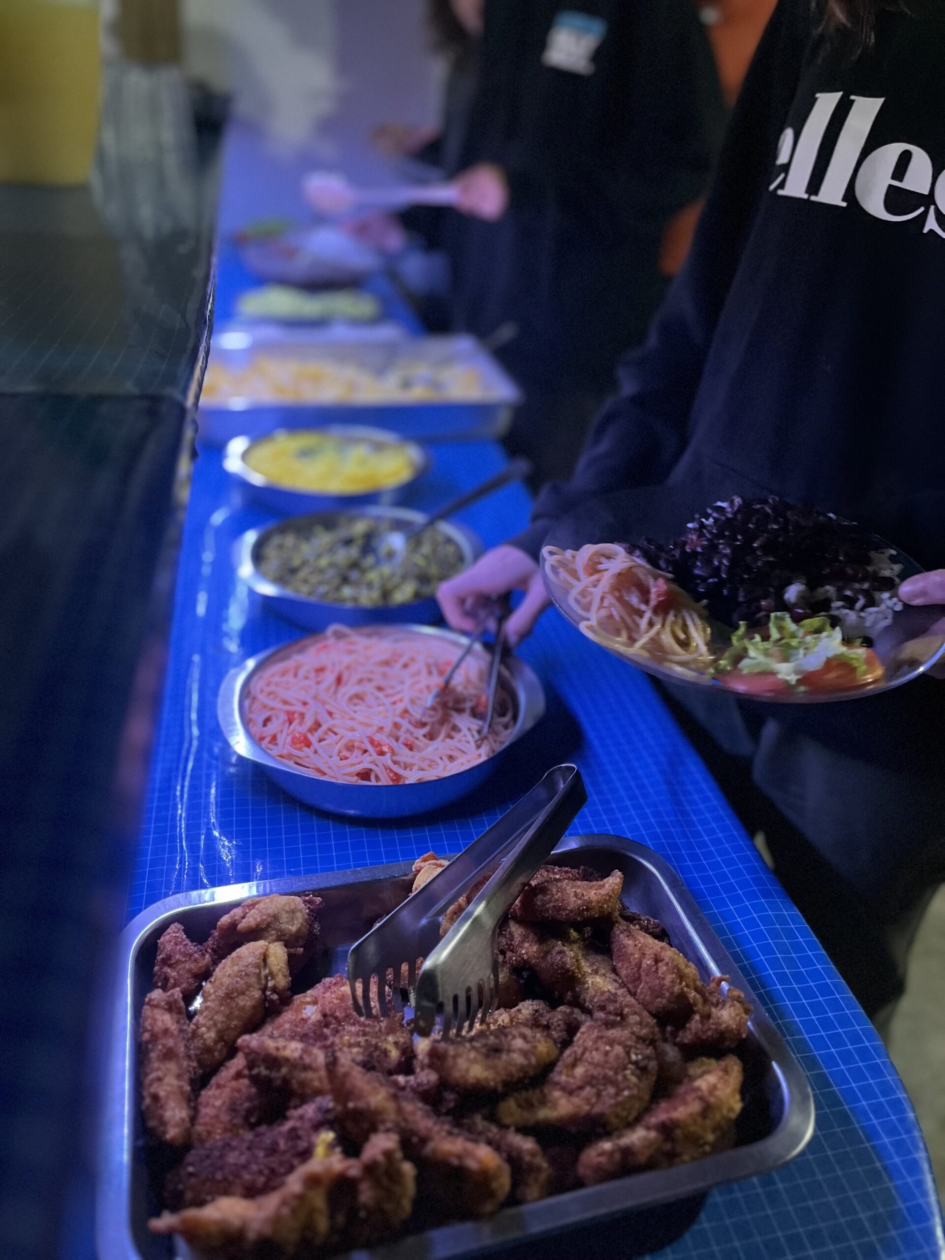 Fuel for the trail — generous, home-cooked and all yours. A long buffet line of home-cooked dishes including breaded meat, pasta with tomato sauce, lentils, and fresh salad, served during a Chapada Diamantina trek meal stop