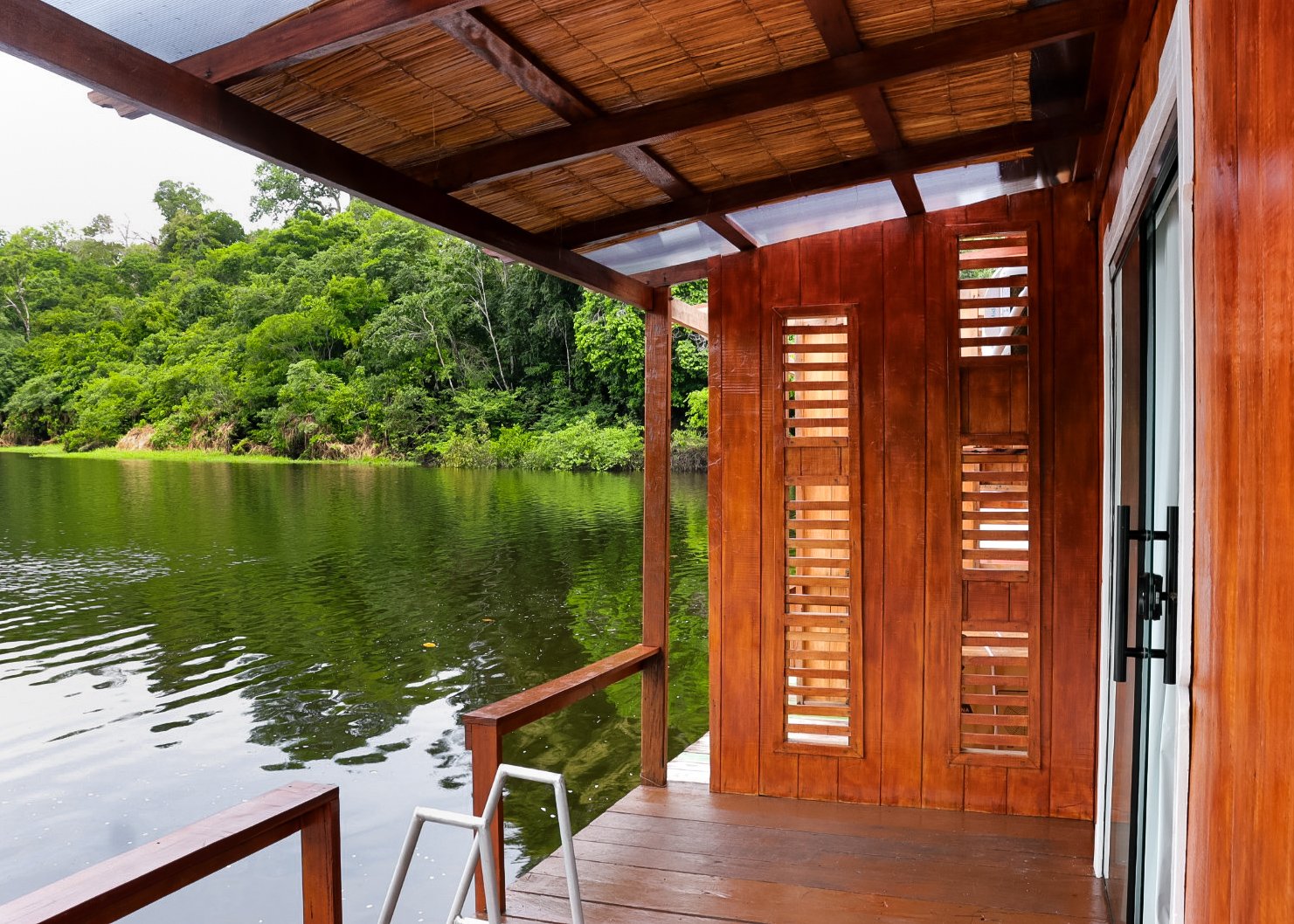 Covered wooden deck of the Eco Floating Lodge with a ladder leading down to the green river