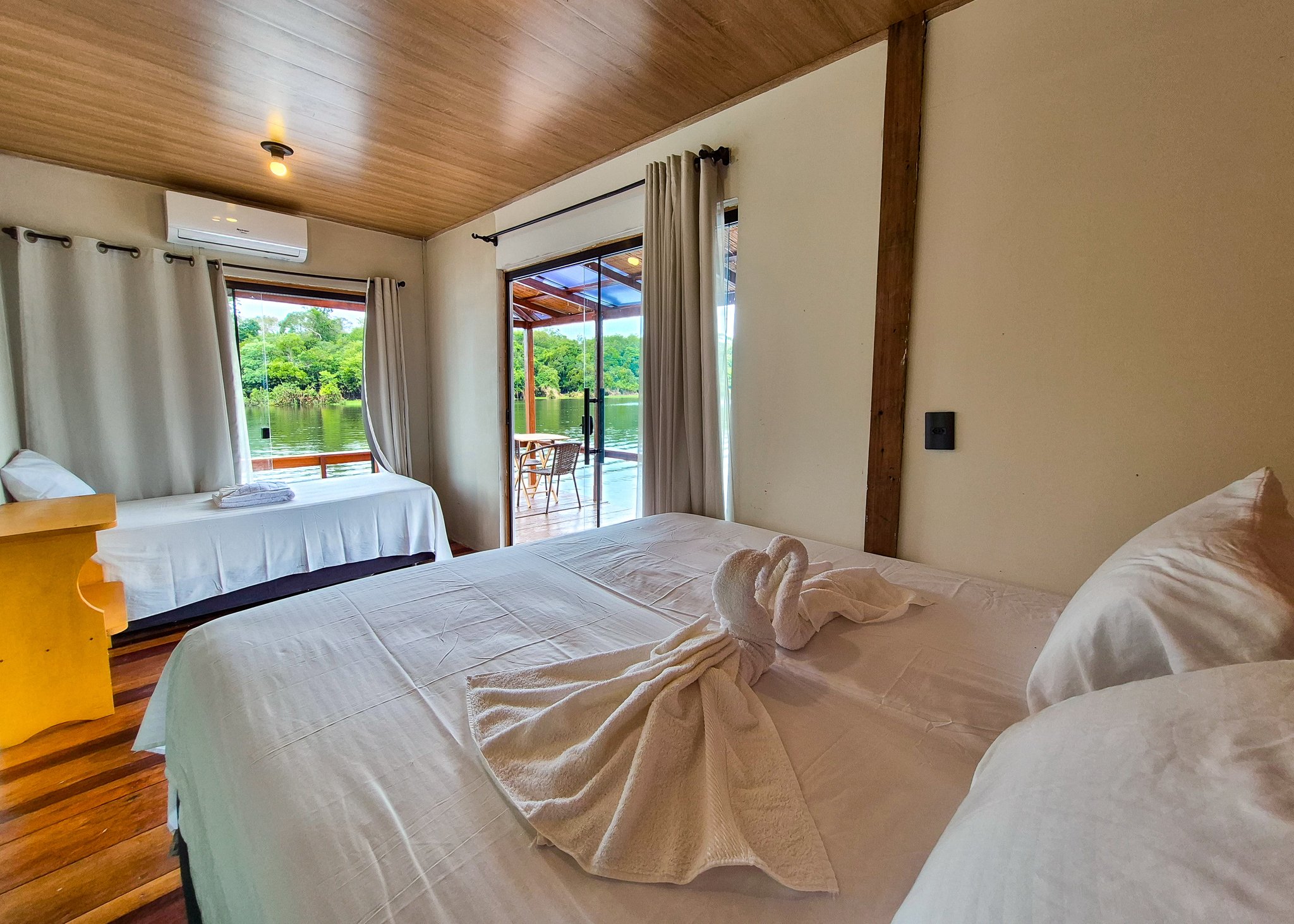 Bright double bedroom at the Eco Floating Lodge with river view through open patio doors