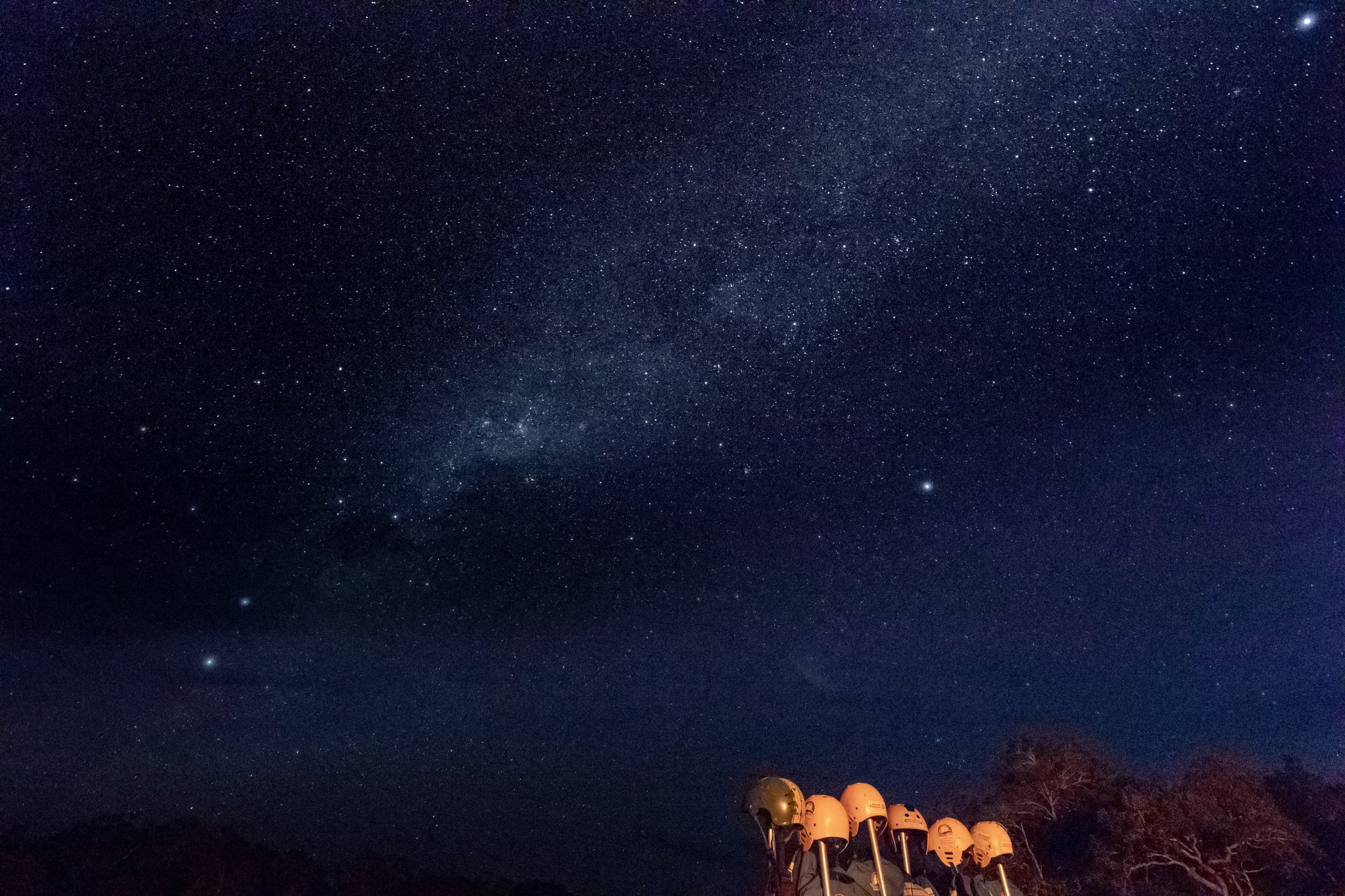 A row of telescopes glowing golden under a vast Milky Way sky during a Jalapão trekking night in the remote cerrado
