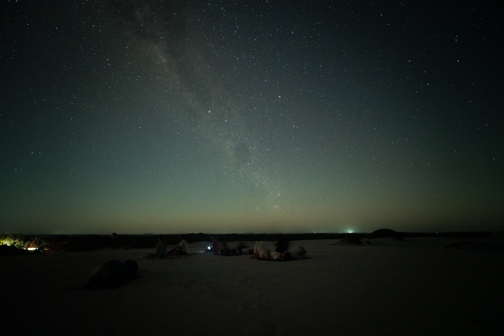 Flat on your back, the galaxy overhead — nowhere else quite like this. A small group of travellers lying on white sand dunes gazing up at the Milky Way arching across a dark, star-filled sky on a lençóis maranhenses trek