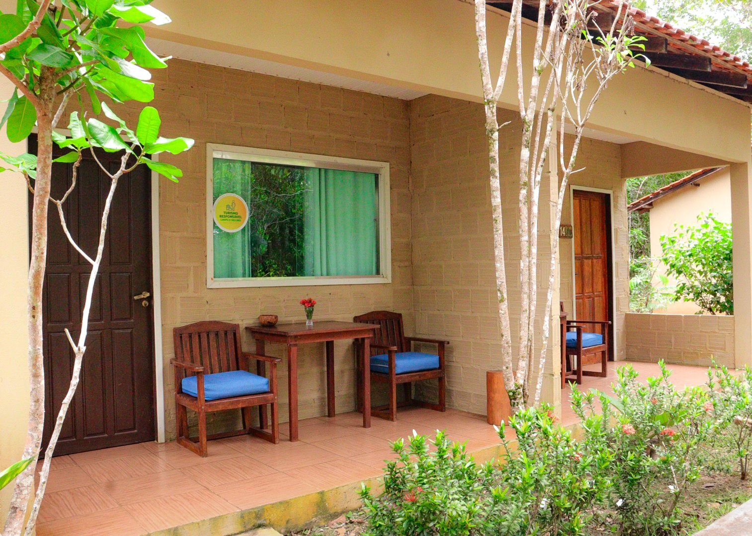 The masonry bungalow's porch offers a shady spot to unwind after a day out. Exterior porch of a masonry bungalow with blue-cushioned chairs and a table in the Amazon