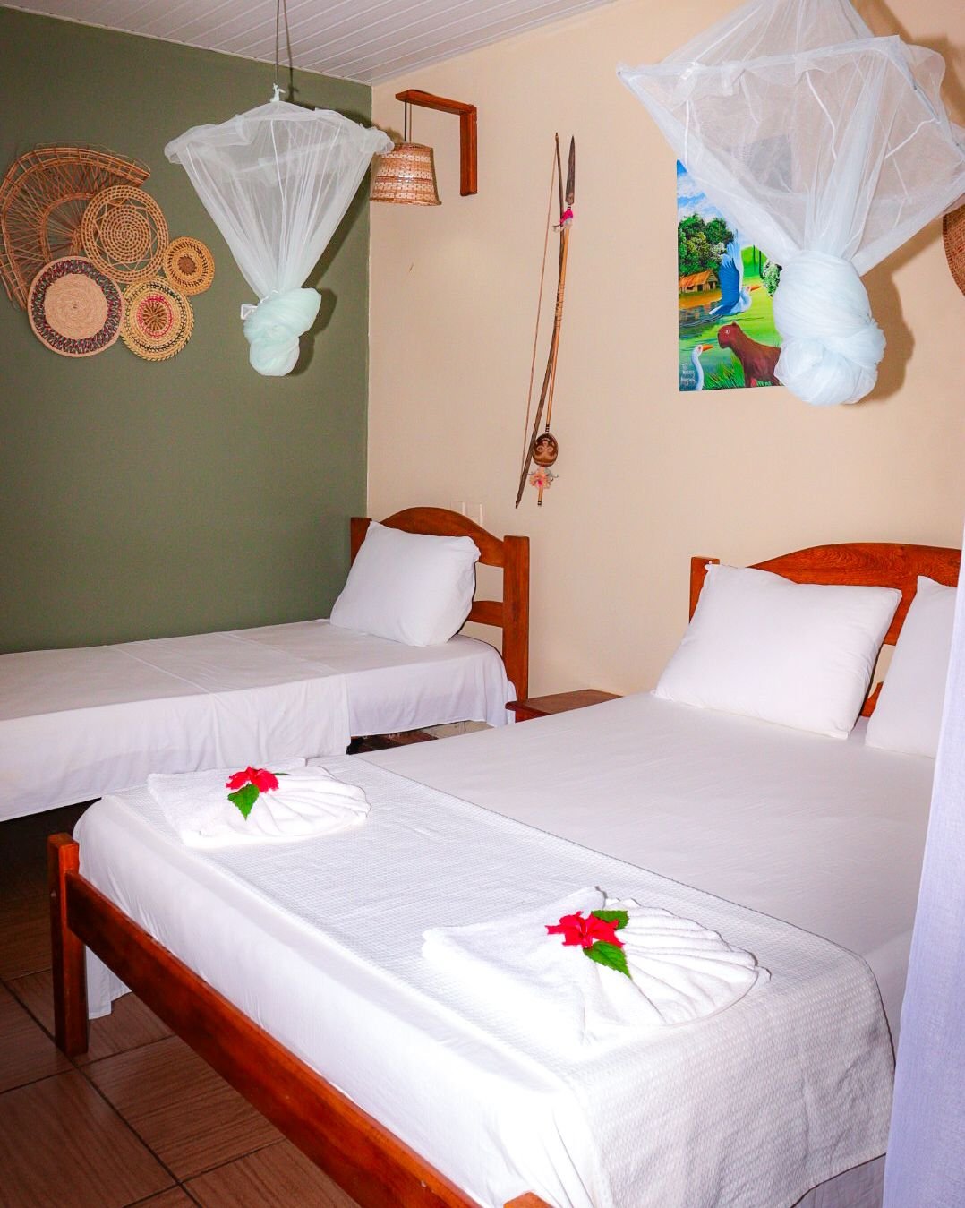 Twin beds and woven baskets bring a regional warmth to the masonry bungalow. Masonry bungalow twin room with two single beds, mosquito nets and woven-basket wall decor in the Amazon