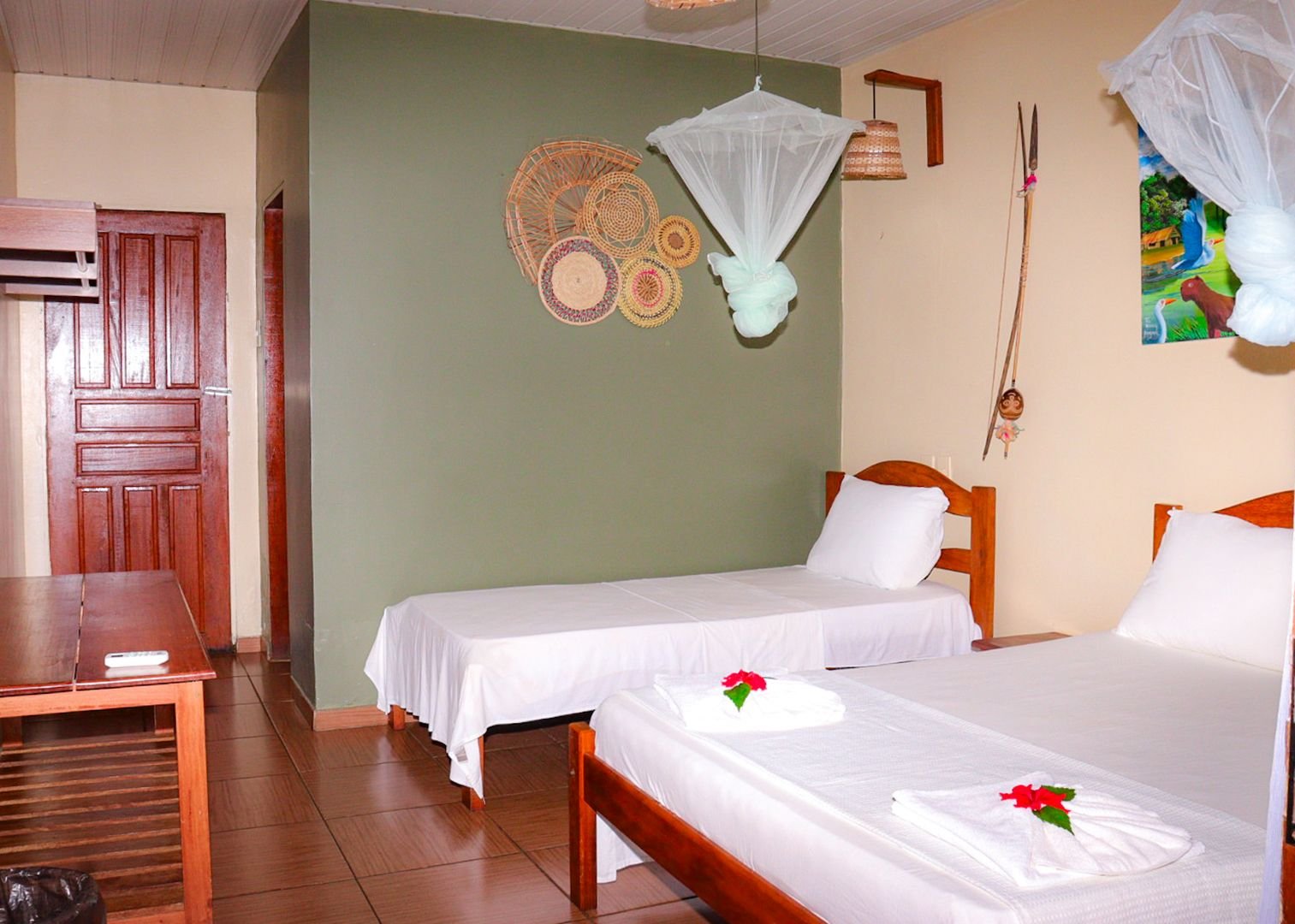 A green accent wall and woven baskets warm up the masonry comfort bungalow. Masonry comfort bungalow twin room with a green accent wall, woven baskets and mosquito nets in the Amazon