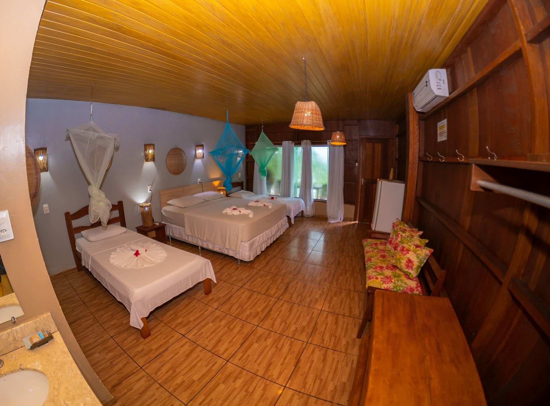 Bright and roomy, the superior family bungalow comes with its own bathroom. Superior family bungalow interior with multiple beds, turquoise nets and an en-suite bathroom in the Amazon