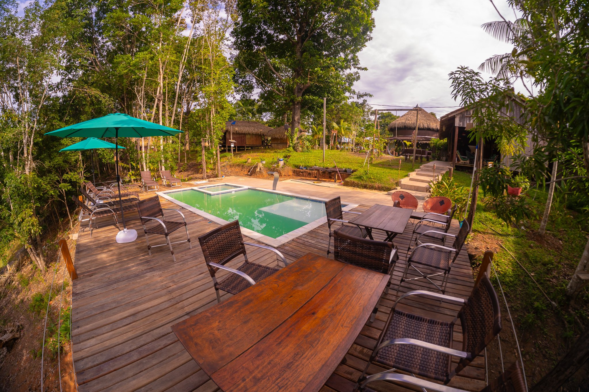 Small swimming pool and wooden deck with loungers in the jungle garden of Turtle Lodge