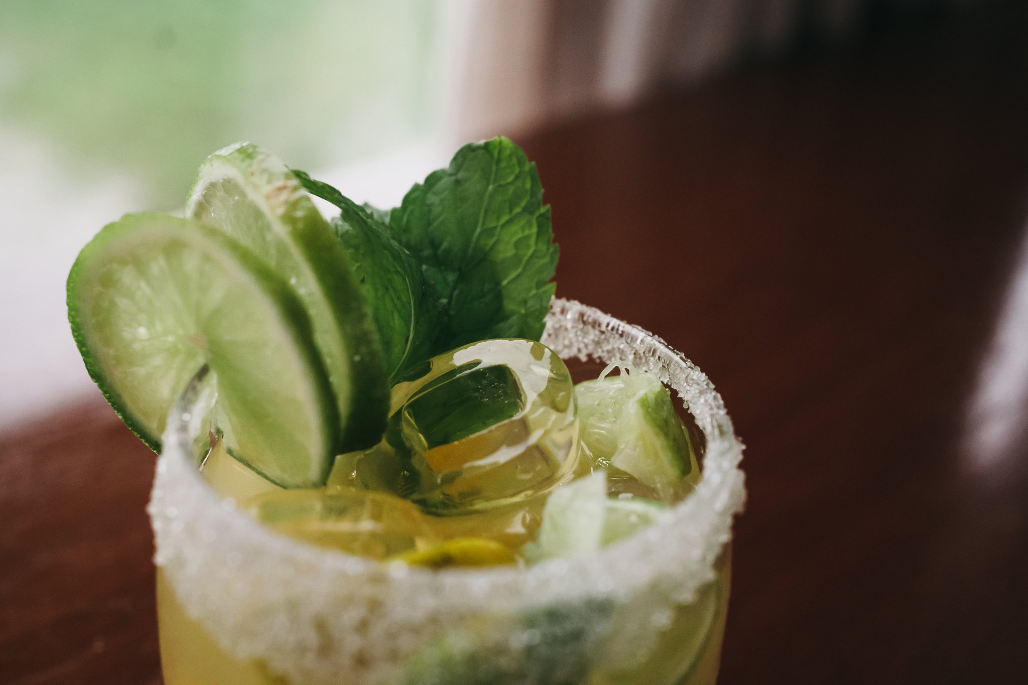 A sugar-rimmed glass garnished with cucumber slices, lime wedges and fresh mint leaves, served on the untamed amazon cruise