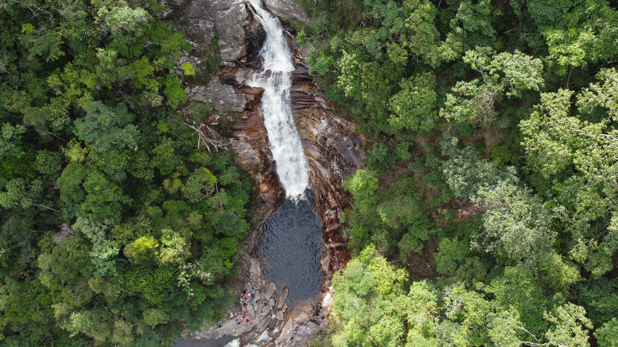 Luftaufnahme eines Wasserfalls, der in einen dunklen Gumpen inmitten dichten Waldes der Chapada Diamantina stürzt, Brasilien