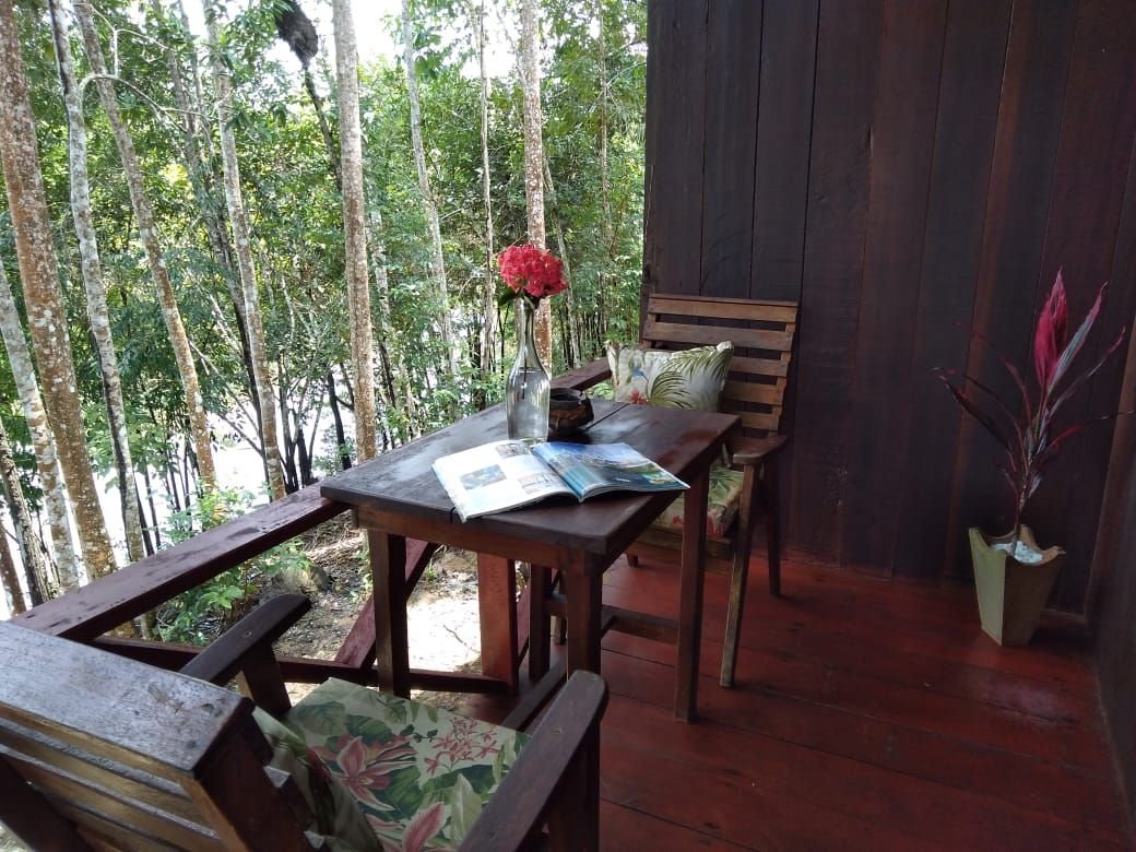 A private porch with forest views is the perfect spot for morning coffee. Wooden bungalow porch with a table, chairs and flowers overlooking the forest in the Amazon